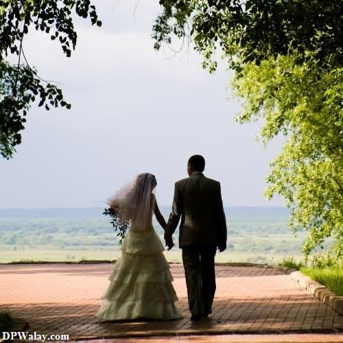 a bride and groom walking down a path-P3YY images by DPwalay
