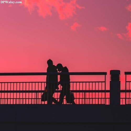a couple kissing on a bridge at sunset 