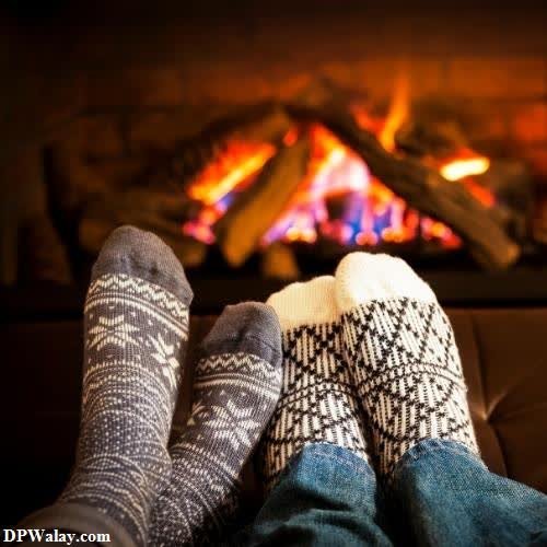 a person's feet in socks and mits, with a fireplace in the background 