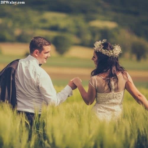 a couple walking through a field holding hands 