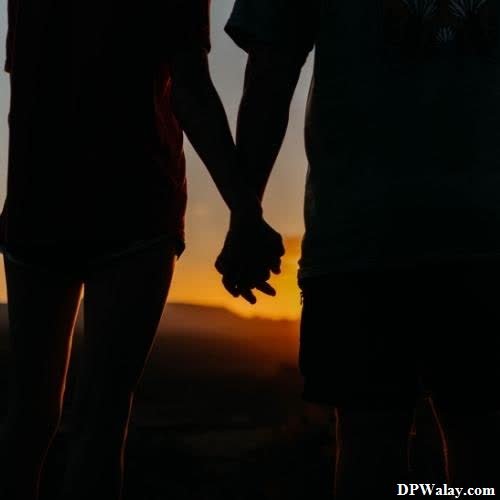 a couple holding hands at sunset