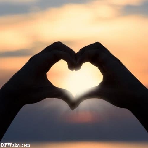 two hands making a heart shape with the sun setting in the background romantic dp for whatsapp 