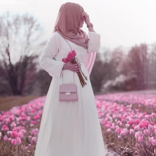 a woman in a white dress standing in a field of pink tulips images by DPwalay