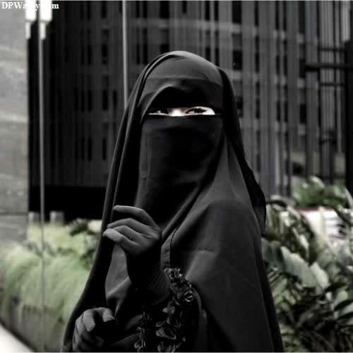 a woman in a black veil walks down a street