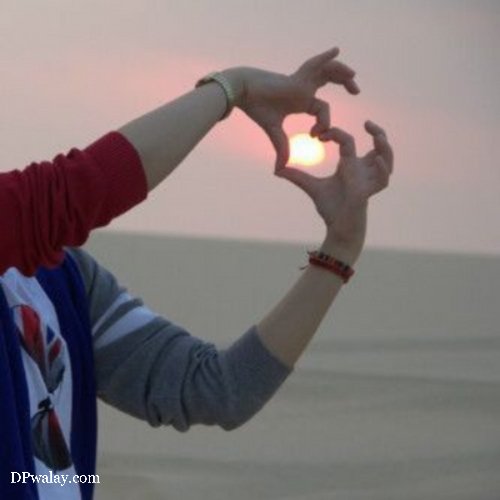 a woman in a red shirt and blue scarf is making a heart with her hands