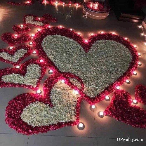 a heart shaped arrangement with candles and flowers