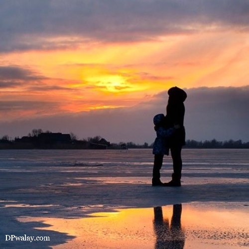 person standing on frozen lake at sunset