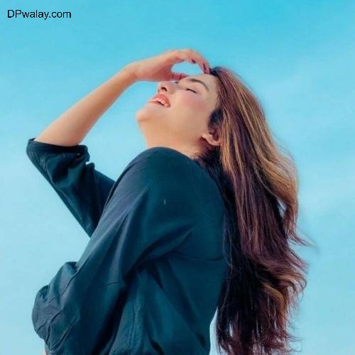 woman with long hair and black shirt is looking up at the sky