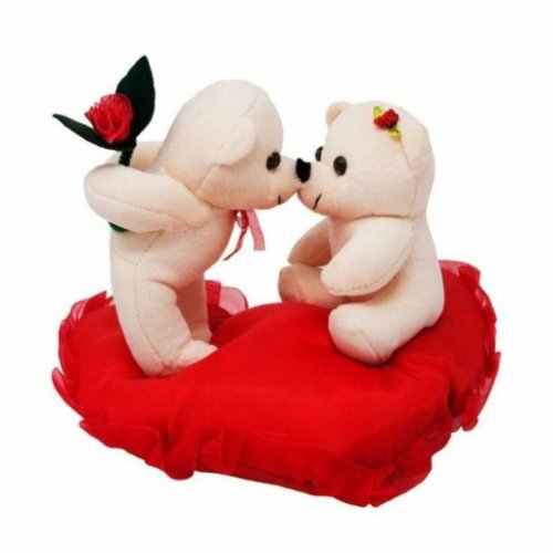 two teddy bears sitting on a red pillow