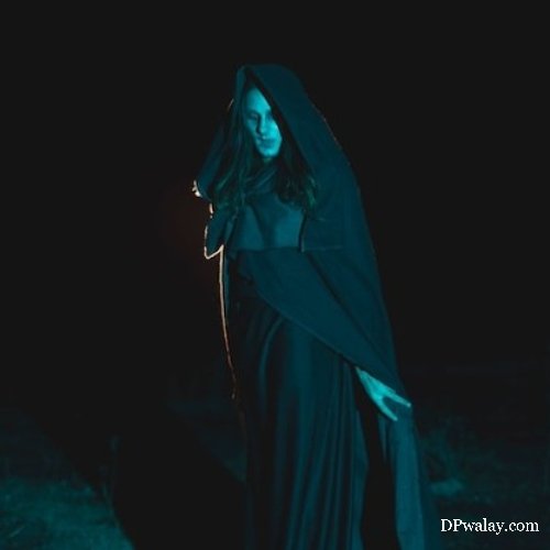 woman in black cloak standing in the dark